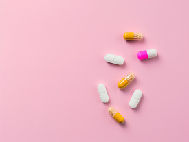 medical tablets and capsules on a pink background