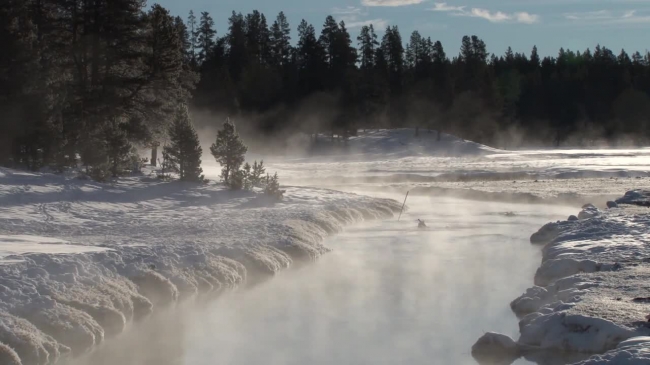 snow covered river banks with steam