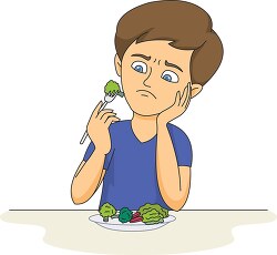 boy holding a fork with vegetables looking unhappy