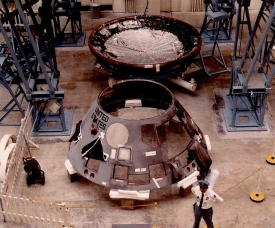 an officer stands guard in front of the disassembled Apollo 204