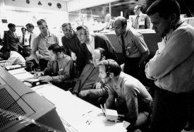 astronauts and flight controllers monitor the console activity