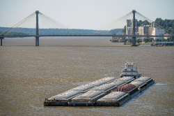 barge on the mississippi river moving towards bridge