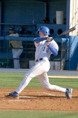 baseball player swings bat at ball