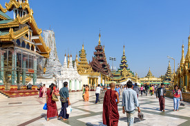 Buddhist monk in traditional robes walking Shwedagon Pagoda in Y