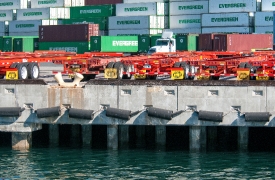 cargo ship containers stacked along harbor