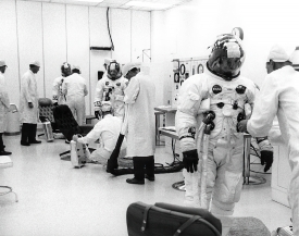 Command pilot of the Apollo 7 is assisted by a suit technician