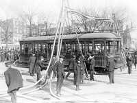 Firemen with hoses over streetcar 1925