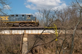 freight train traveling over creek on bridge