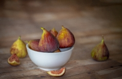 group of figs in a white bowl wood background photo