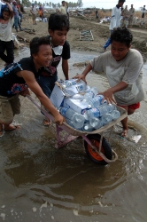 Indonesian kids carry bottles of drinking water in a wheelbarrow