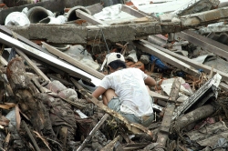 Indonesian man looks through debris