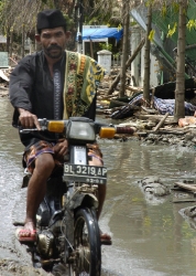 Indonesian man rides through the devastated streets