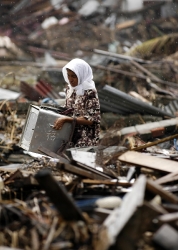 indonesian Woman searches through debris in the rain