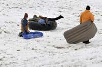 kids playing tubing down hill in snow