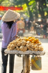 lady pushing bicycle with basket of potatoes  Vietnam