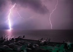 lighting flashes as the aircraft carrier transits the strait of 