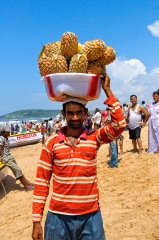 Man holding tub of pineapples on his head, goa india