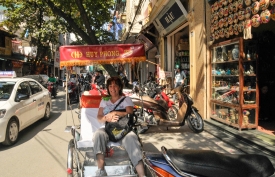 tourist sitting in bike cab parked on street in hanoi