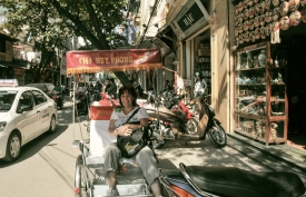 tourist sitting in bike cab parked on street in hanoi
