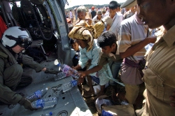 US military personel passes out water to victims