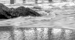 waves breaking on rocks beach black white photo
