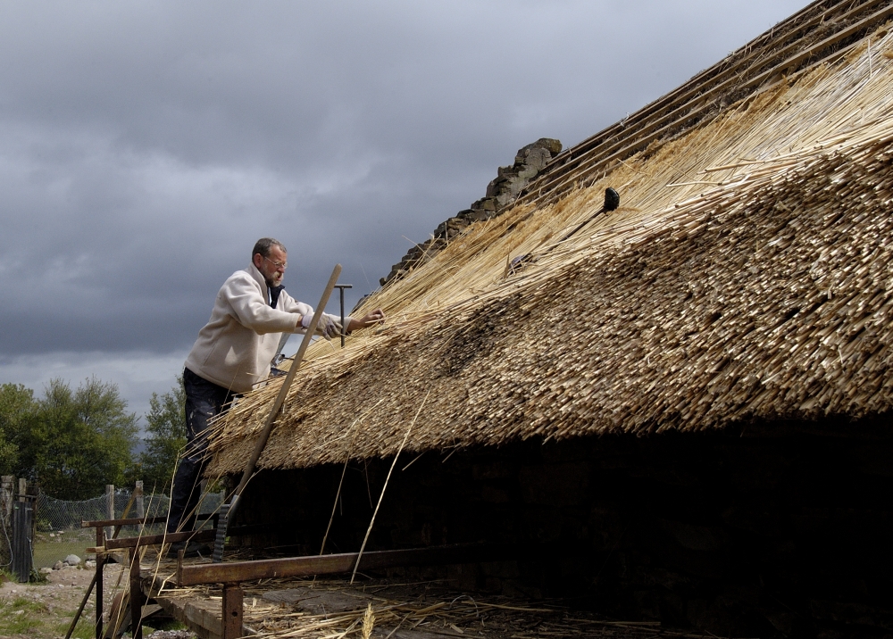 A thatcher working on cottage roof in Ireland