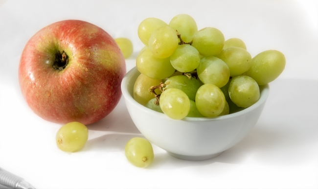 bowl green grapes with single red apple wood background photo