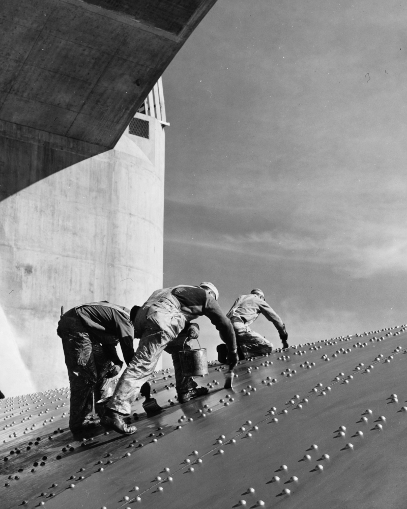 construction workers painting on wall of steel