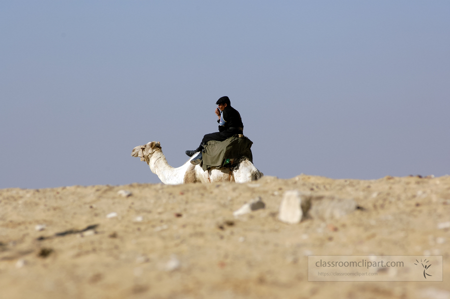 egyptain guard sitting on camel in the desert near the pyramids