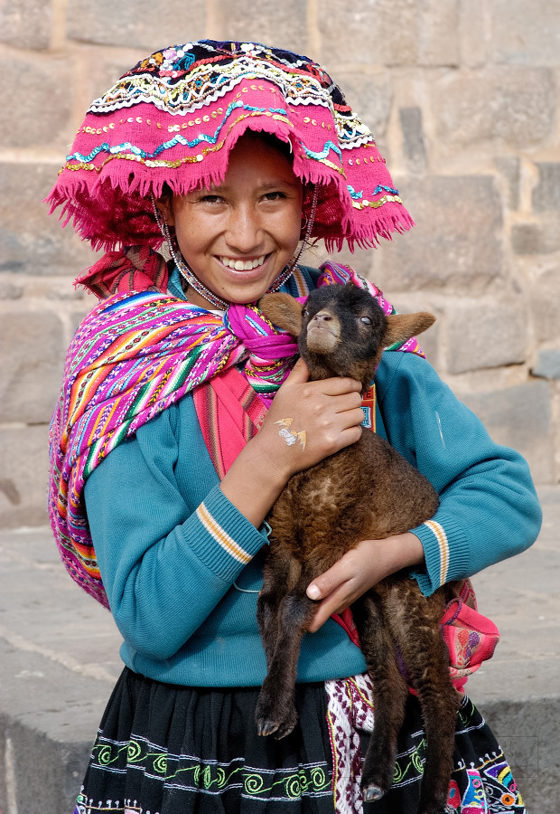 Girl in traditional dress holding a baby Alpaca