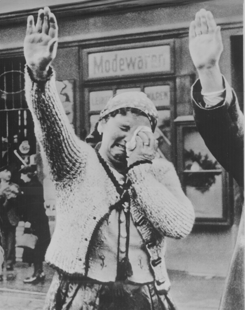 Sudeten woman unable to conceal her misery as she dutifully salutes the triumphant Hitler