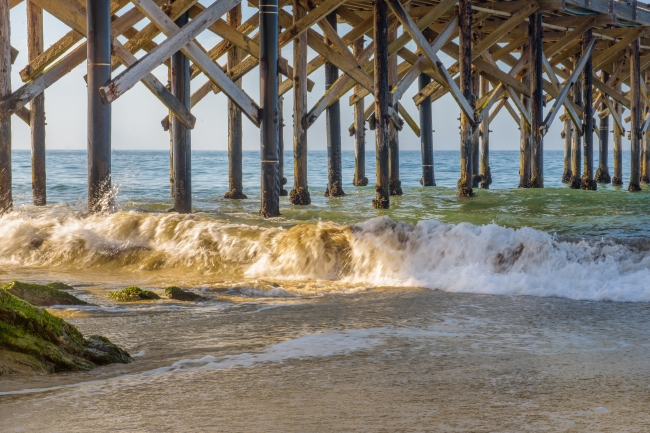 waves hitting wooden pier goletta beach california