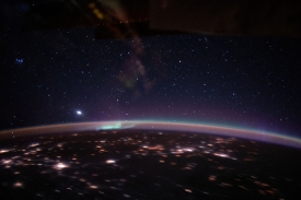 an aurora accents earths atmospheric glow underneath a starry sk