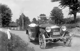 Automobile driving on country road early 1900