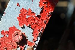 Close up of red paint peeling off a metal surface