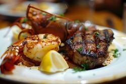 cooked lobster shrimp and grilled steak garnished with a sprig o