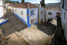 looking down at white washed building cobble stone street obidos