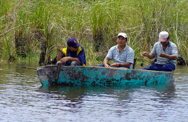 Men in small boat fishing in river