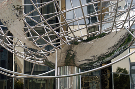 metallic globe structure with a skyscraper in the background