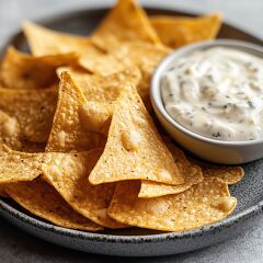 plate of golden tortilla chips served with a bowl of creamy dip