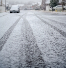 snow covered nieghborhood road with car tire tracks