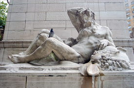 stone sculpture of a reclining figure with a pigeon perched on i