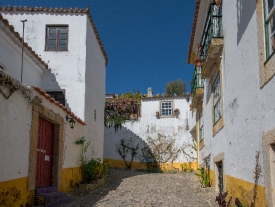 white washed yellow trimmed building cobble stone street obidos 