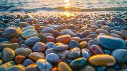 wide shot of a beach covered in smooth colorful pebbles at sunse