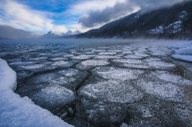 winter ice patterns on lake mcdonald with blue sky clouds
