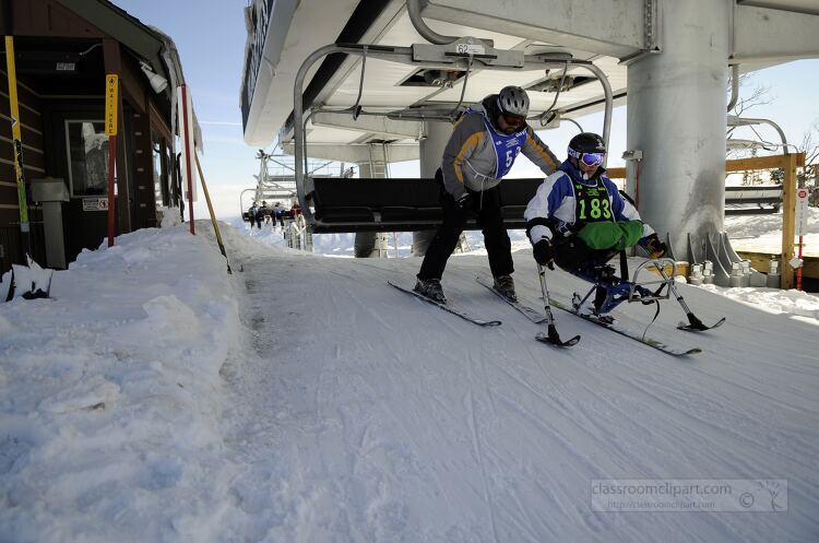 sit skier being assisted at the top of a ski slope