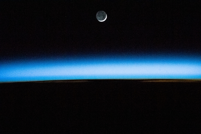 the waxing crescent moon is pictured above earths atmosphere