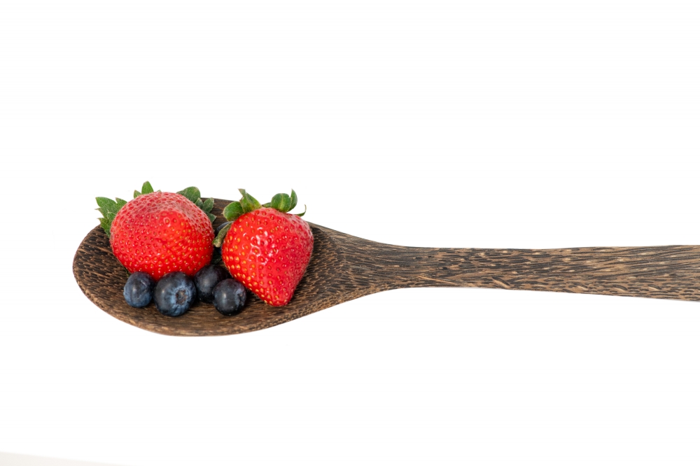 wooden spoon with strawberries and blueberries white background