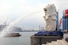 Merlion fountain spouting water in bustling Singapore harbor