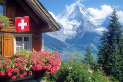 Swiss Mountain House With Flowers and Flag Near Peaks